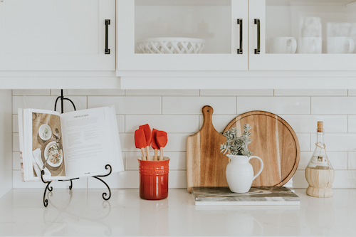 kitchen counter subway tile cabinets spatulas in red vase cutting boards wood