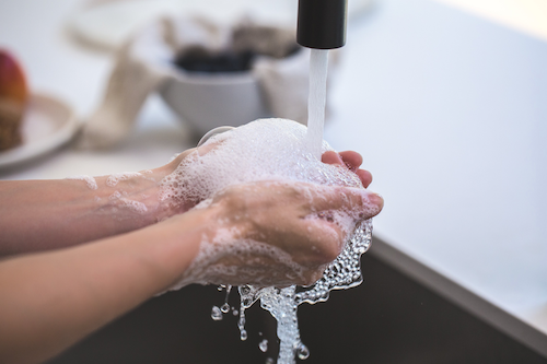 person washing hands with soap water outdoor furniture lakeside living maintenance